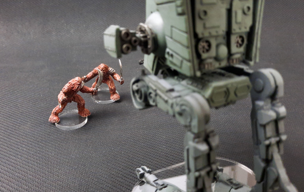 Showcase: bemalte Plastik-Miniature aus dem Star Wars Brettspiel Imperial Assault: 2 Wookiee-Krieger stellen sich einem AT-ST entgegen; auf durchsichtiger Acryl Base vor schwarzem Hintergrund