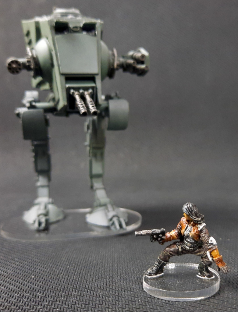 Showcase: bemalte Plastik-Miniature aus dem Star Wars Brettspiel Imperial Assault: Jyn Odan und AT-ST Walker auf durchsichtiger Acryl Base vor schwarzem Hintergrund