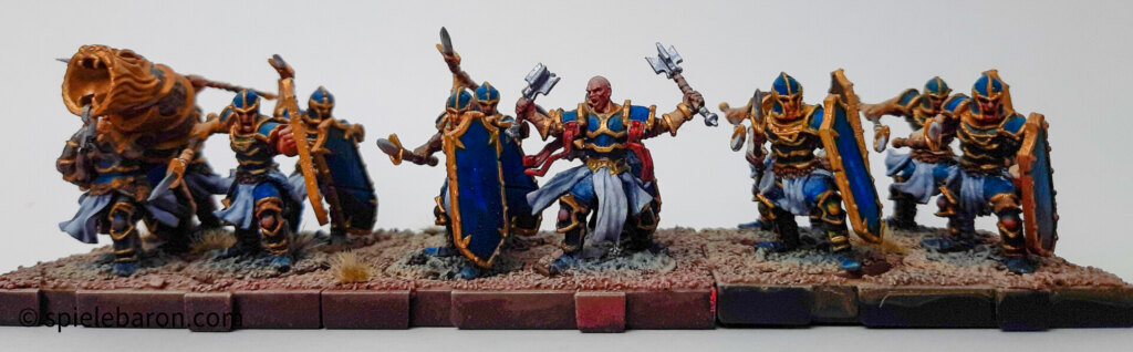 Showcase Runewars Tabletop Daqan Armee, bemalt: Infanterie mit Verstärkungen; Farbschema: Blau-Gold-Rot vor weißem Hintergrund