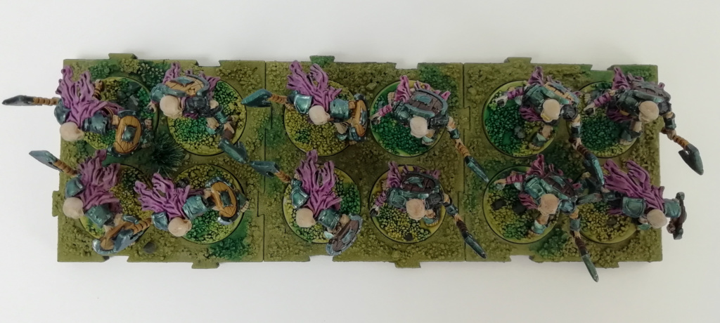 Showcase Runewars Tabletop Miniaturen: Untote Waiqar Skelett Armee: Infanterie mit Äxten, bemalt im Farbschema Blau-Metallic und Violett auf grünen Bases