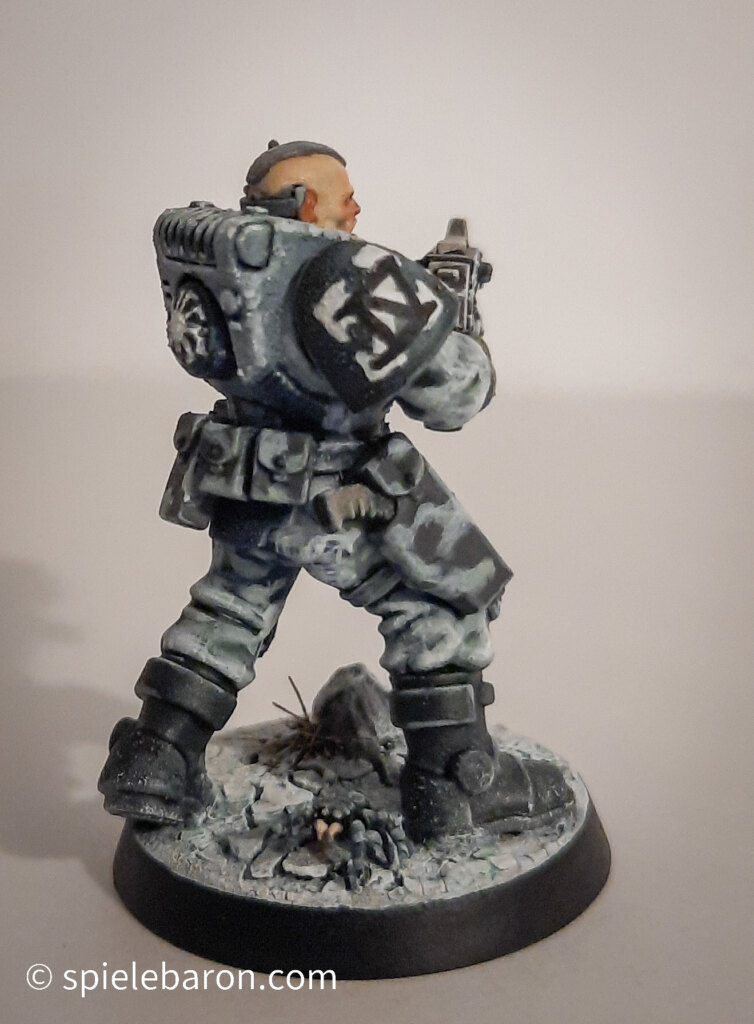 Foto eines Space Marine Primaris Scouts mit Boltgewehr in Winter-Camouflage, bemalt mit Winterbase vor weißem Hintergrund; seitlich von hinten