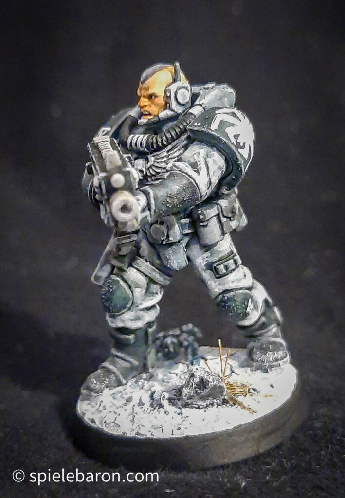 Foto eines Space Marine Primaris Scouts mit Boltgewehr in Winter-Camouflage, bemalt mit Winterbase vor schwarzem Hintergrund; seitlich frontal