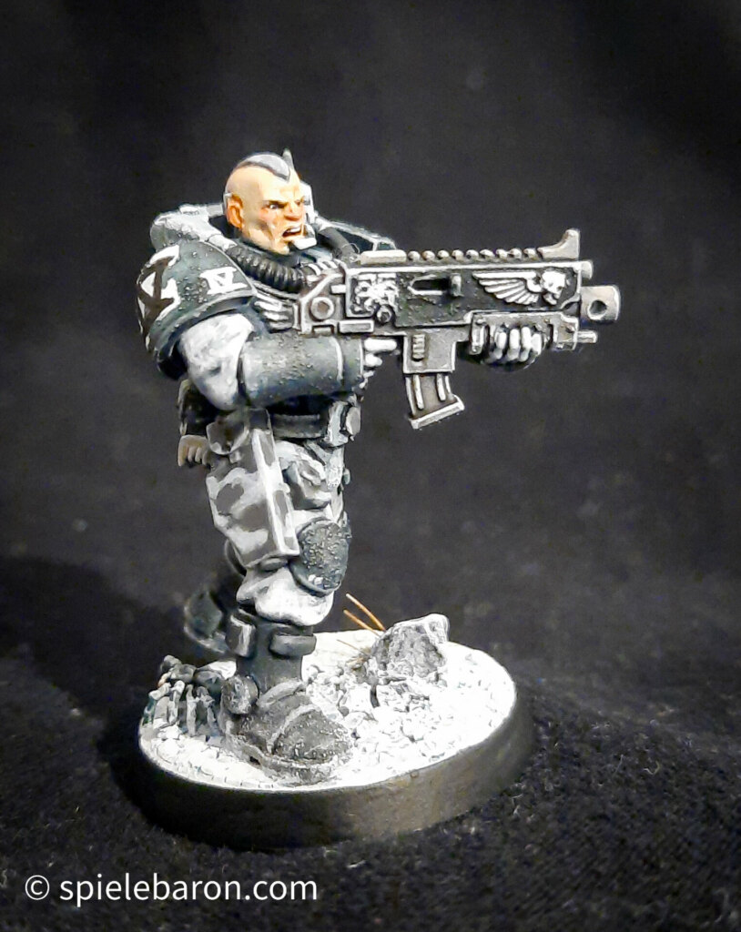 Foto eines Space Marine Primaris Scouts mit Boltgewehr in Winter-Camouflage, bemalt mit Winterbase vor schwarzem Hintergrund; seitlich frontal